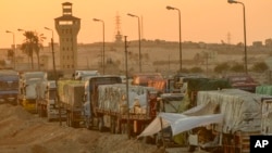 (FILE) Trucks of humanitarian aids wait to cross the Rafah border crossing between Egypt and the Gaza Strip, in Rafah, Egypt, Sept. 9, 2024.