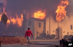 A man walks in front of the burning Altadena Community Church, Jan. 8, 2025, in the downtown Altadena section of Pasadena, California.