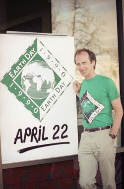 FILE - Earth Day founder Denis Hayes poses with an Earth Day sign outside Earth Day headquarters in Palo Alto, California on April 21, 1990.