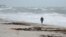 A beach goer walks along the shore as waves churned up by Tropical Storm Isaias crash near Jaycee Beach Park, in Vero Beach, Florida, Aug. 2, 2020. 