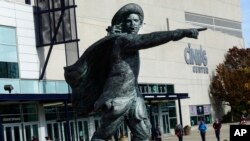 FILE - Pedestrians pass a statue of D'Artagnan, the mascot of the Xavier University Musketeers basketball program at the Cintas Center, Oct. 31, 2017, on the Xavier University campus in Cincinnati. 