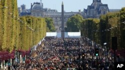 FILE - People walk on the Champs Elysees during the "day without cars," in Paris, Sept. 27, 2015.