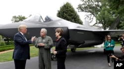 President Donald Trump talks with Lockheed Martin president and CEO Marilyn Hewson and director and chief test pilot Alan Norman in front of a F-35 as he participates in a "Made in America Product Showcase" at the White House, July 23, 2018.