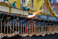 FILE - A worker welds on the Ninth Street bridge under reconstruction in Pittsburgh, Pennsylvania, May 6, 2020.