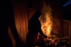Zairi Olivia, a member of the Israelites of the New Universal Pact religious group, lights a fire to cook dinner inside her house in Jose Carlos Mariategui, Peru, March 31, 2021.