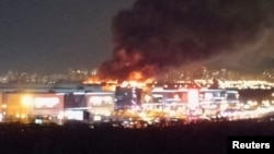 Дым поднимается над горящей концертной площадкой «Крокус Сити Холл» после сообщения об инциденте со стрельбой на окраине Москвы, Россия, 22 марта 2024 года.