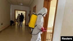 FILE - A health agent wearing protective equipment disinfects the corridors amid the spread of the coronavirus, at an hospital in Douala, Cameroon, April 27, 2020.