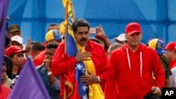 Venezuela's President Nicolas Maduro holds the Venezuelan flag next to singer "El Potro Alvarez" during a rally in Caracas, Venezuela, July 27, 2017. 