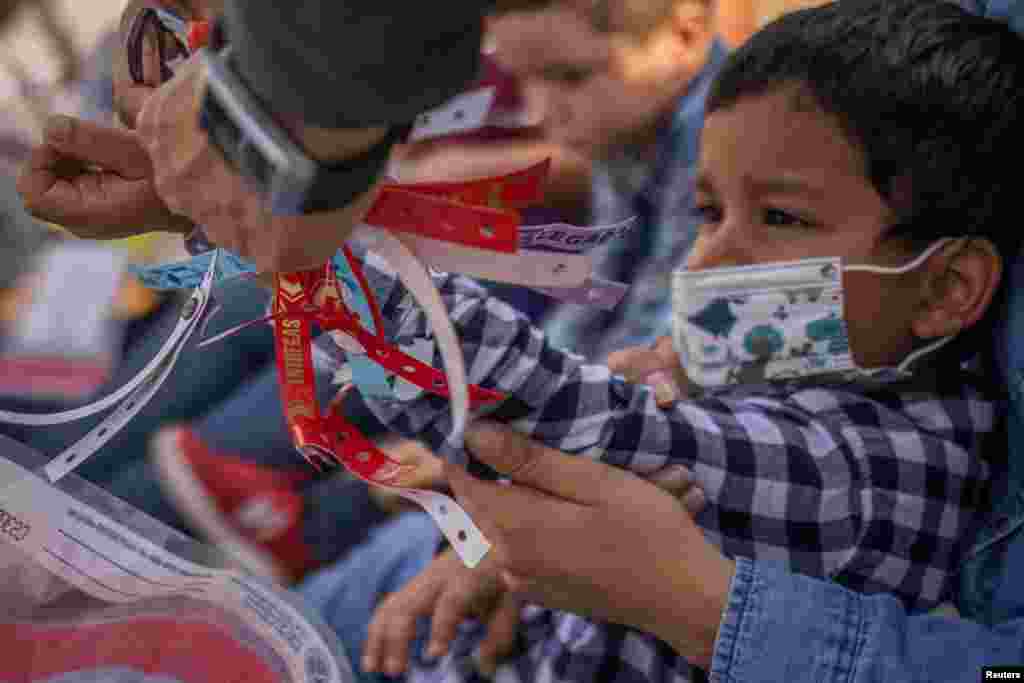 A U.S. Border Patrol Agent removes a wristband of Santiago, a four-year-old asylum seeking migrant boy from Honduras, after he crossed the Rio Grande river into United States from Mexico with his mother in Penitas, Texas, March 9, 2021.