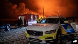 A police vehicle is parked at the entrance of the road to Grindavík with the eruption in the background, near Grindavik on Iceland's Reykjanes Peninsula, Dec. 18, 2023.