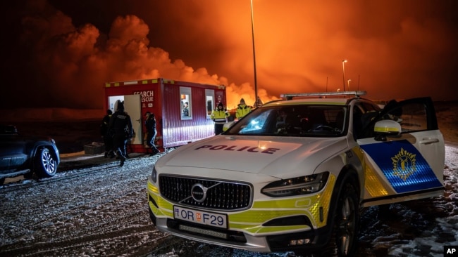A police vehicle is parked at the entrance of the road to Grindavík with the eruption in the background, near Grindavik on Iceland's Reykjanes Peninsula, Dec. 18, 2023.