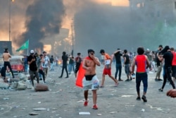 Anti-government protesters set fires and close a street during a demonstration in Baghdad, Oct. 3, 2019.
