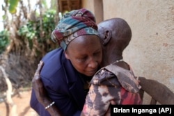 Emelyne Nzeyimana, left, and Prudencienne Namukobwa, perform akazehe, a Burundian traditional form of musical greeting performed exclusively by women, outside her home in Ngozi, Burundi, Friday, Sept. 20, 2024. (AP Photo/Brian Inganga)