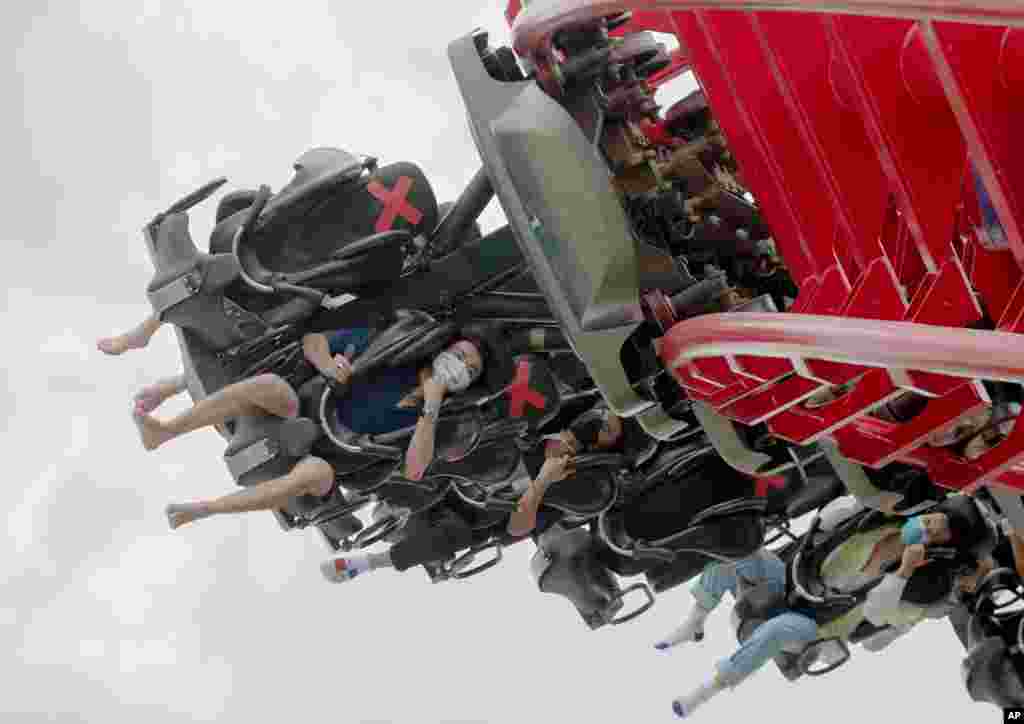 Visitors wearing face masks ride the "Vortex" roller coaster at the recently reopened Siam Amazing Park in in Bangkok, Thailand.