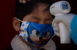 Un médico toma la temperatura de un niño durante una campaña de detección del coronavirus en Villa El Tejar, La Paz, Bolivia, el domingo 5 de julio de 2020.