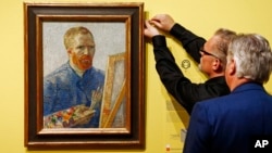 Kurator memasang lukisan potret Vincent Van Gogh yang digambar sendiri oleh sang seniman, di Museum Van Gogh di Amsterdam, Belanda.