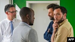 French journalist for Le Monde newspaper, Jean Philippe Remy (2nd R) and British freelance photographer Phil Moore (R), speak with the French Ambassador to Burundi Gerrit van Rossum (L) and Fleury Nyomana, Deputy Head of Office in Bujumbura British Embassy (2nd L) in the hall outside the prosecutor's office in Bujumbura, Jan. 29, 2016.