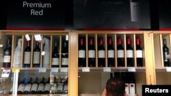 Bottles of Penfolds Grange, made by Australian wine maker Penfolds and owned by Australia's Treasury Wine Estates, are displayed as a shop assistant places more wine bottles onto shelves below at a wine shop in central Sydney, Australia.