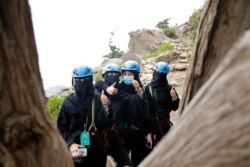 Saudi tourists wear helmets and keep their faces and hair covered according to local custom, as they pose for a photo before zip lining between cliffs, during the al-Soudah festival in Abha, southwest Saudi Arabia, Aug. 23, 2019.