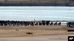 Familiares de las víctimas de una colisión en el aire entre un avión de American Airlines y un helicóptero del Ejército caminan cerca del lugar de los restos en el río Potomac en el Aeropuerto Nacional Ronald Reagan de Washington, el 2 de febrero de 2025, en Arlington, Virginia