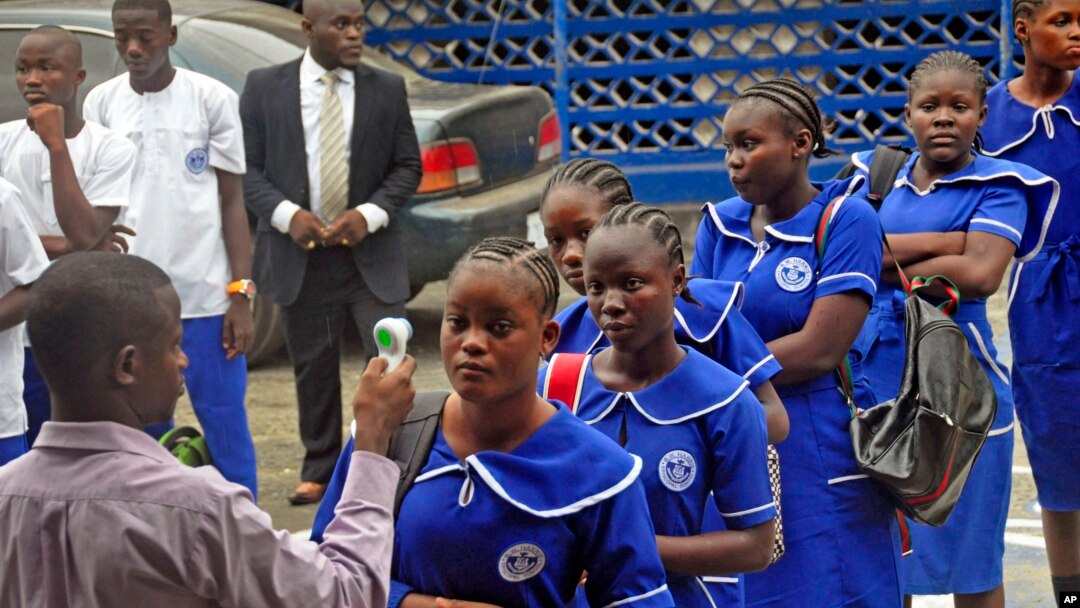A Liberian school teacher (L) takes the temperature of students arriving for morning lessons at school, as part of the Ebola prevention measures at the BW Harris High School in Monrovia, Feb. 16, 2015.