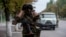 FILE - A Ukrainian government soldier from battalion "Donbass" looks through a binocular at a checkpoint next to their positions in village Mariinka near Donetsk, eastern Ukraine, Aug. 11, 2014.