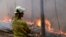 A firefighter keeps an eye on a controlled fire as they work at building a containment line at a wildfire near Bodalla, Australia, Jan. 12, 2020. 