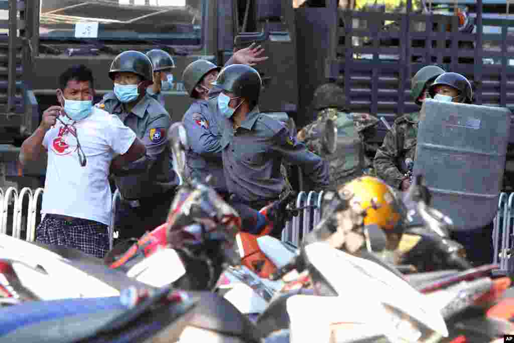 Police arrest a man during a crackdown on anti-coup protesters holding a rally in front of the Myanmar Economic Bank in Mandalay, Myanmar.