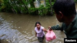 কেলানিয়া অঞ্চলের বন্যা কবলিত এলাকায় এক নারী শ্রী লঙ্কান সেনাবাহিনী থেকে সাহায্য গ্রহণ করছেন। ফটোঃ ৪ জুন, ২০২৪। 