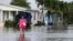 FILE - A woman walks near her flooded neighborhood in Davie, Florida, June 7, 2017. With Hurricane Irma bearing down on Florida, data shows that across the peninsula's 38 coastal counties, just 42 percent of homes in potential hazards zones are insured against flood damage.