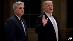 El presidente Donald Trump, acompañado del líder de la mayoría en la Cámara de Representantes de EE.UU., Kevin McCarthy, de California, habló con la prensa a su llegada a una cena en el Club de Golf Trump International en West Palm Beach, Florida, el domingo, 14 de enero de 2018.