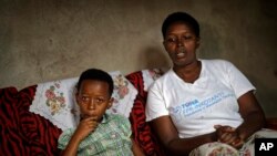 FILE—In this photo taken April 4, 2019, genocide survivor Jannette Mukabyagaju, 42, recounts her experience as her 8-year-old daughter Natasha Umutesi listens, in their home in the reconciliation village of Mbyo, near Nyamata, in Rwanda.