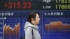 A woman walks by an electronic stock board of a securities firm in Tokyo, Feb. 1, 2016. Chinese stocks fell Monday after a weak manufacturing report. Other markets were mixed. 