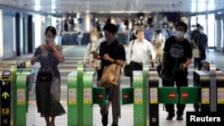 Para pengunjung mengenakan masker saat melewati pintu otomatis menuju stasiun kereta api di Tokyo, Jepang, di tengah pandemi Covid-19, 23 Juli 2020. 