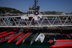 A man thought to be a migrant who made the crossing from France is escorted along a walkway past dinghies after disembarking from a British border force vessel in Dover, south east England, July 22, 2021.