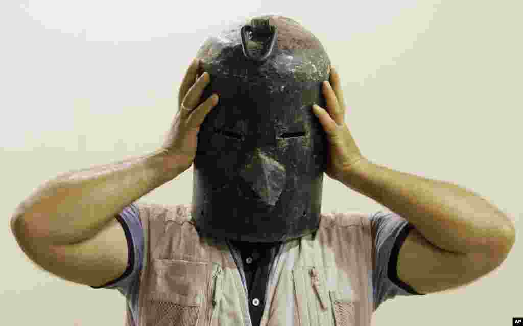 An Iraqi man wears a metal mask used as a torture device by the regime of Iraq&#39;s ousted leader Saddam Hussein at the Shaheed Monument in Baghdad, Iraq.