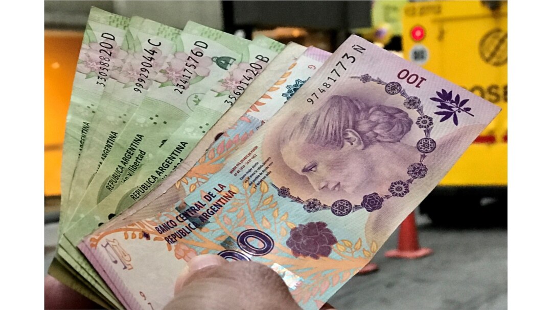 FILE - A man shows Argentine pesos outside a bank in Buenos Aires' financial district, Argentina, Aug. 30, 2018.