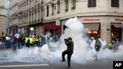 Demonstrators run away through tear gas in Lyon, central France, Dec. 15, 2018.