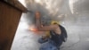 Smokes rises from a fire as a Palestinian protester takes cover during clashes with Israeli troops near the Jewish settlement of Beit El, near the West Bank city of Ramallah.