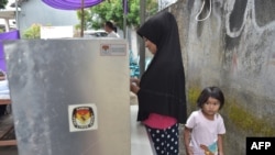 Seorang pemilih sedang menggunakan hak pilihnya di sebuah TPS dalam pilkada Tangerang, Banten, 27 Juni 2018. (Foto: AFP)