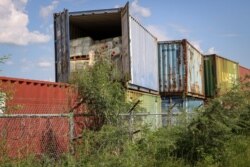 In this photo taken Oct. 1, 2018, shipping containers storing smaller plastic containers used by the oil industry are stacked at a junkyard in Gumry, near Palouch, in South Sudan.