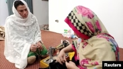 Rani Khan, a transgender woman who teaches the Quran at Pakistan's first transgender only madrasa or a religious school, looks at one of her students during a tailoring lesson in Islamabad, Pakistan March 10, 2021. (REUTERS/Salahuddin)