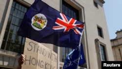FILE - A flag of Hong Kong is waved in front of a placard during a protest against Hong Kong's deteriorating freedoms, outside China's embassy, in London, Britain, July 31, 2020. 