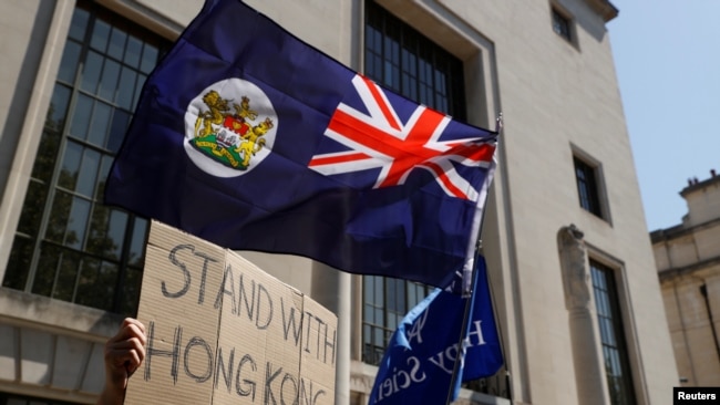 FILE - A flag of Hong Kong is waved in front of a placard during a protest against Hong Kong's deteriorating freedoms, outside China's embassy, in London, July 31, 2020.