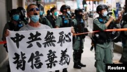 Seorang pengunjuk rasa anti undang-undang keamanan China membentangkan spanduk bertuliskan "Partai Komunis China Tidak Tahu Malu, melanggar janji-janji," dalam unjuk rasa di Hong Kong, China, 1 Juli 2020. (Foto: Reuters)