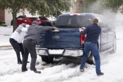Varias personas ayudan a un conductor atascado en la nieve en Round Rock, Texas, el 17 de febrero de 2021.