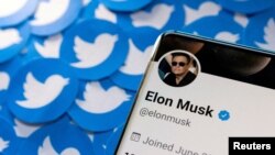 FILE PHOTO: Illustration shows Elon Musk's Twitter profile on smartphone and printed Twitter logos. Taken April 28, 2022
