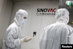 FILE - People work in a laboratory of Chinese vaccine maker Sinovac Biotech, developing an experimental COVID-19 vaccine, during a government-organized media tour in Beijing, China, Sept. 24, 2020.