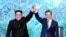 North Korean leader Kim Jong Un, left, and South Korean President Moon Jae-in raise their hands after signing a joint statement at the border village of Panmunjom in the Demilitarized Zone, South Korea, April 27, 2018.