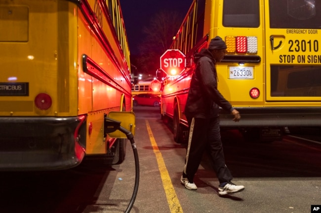 An electric school bus driver examines his safety stop signs before driving to school inside the Montgomery County Schools bus lot, Friday, Feb. 9, 2024, in Rockville, Md. (AP Photo/Tom Brenner)